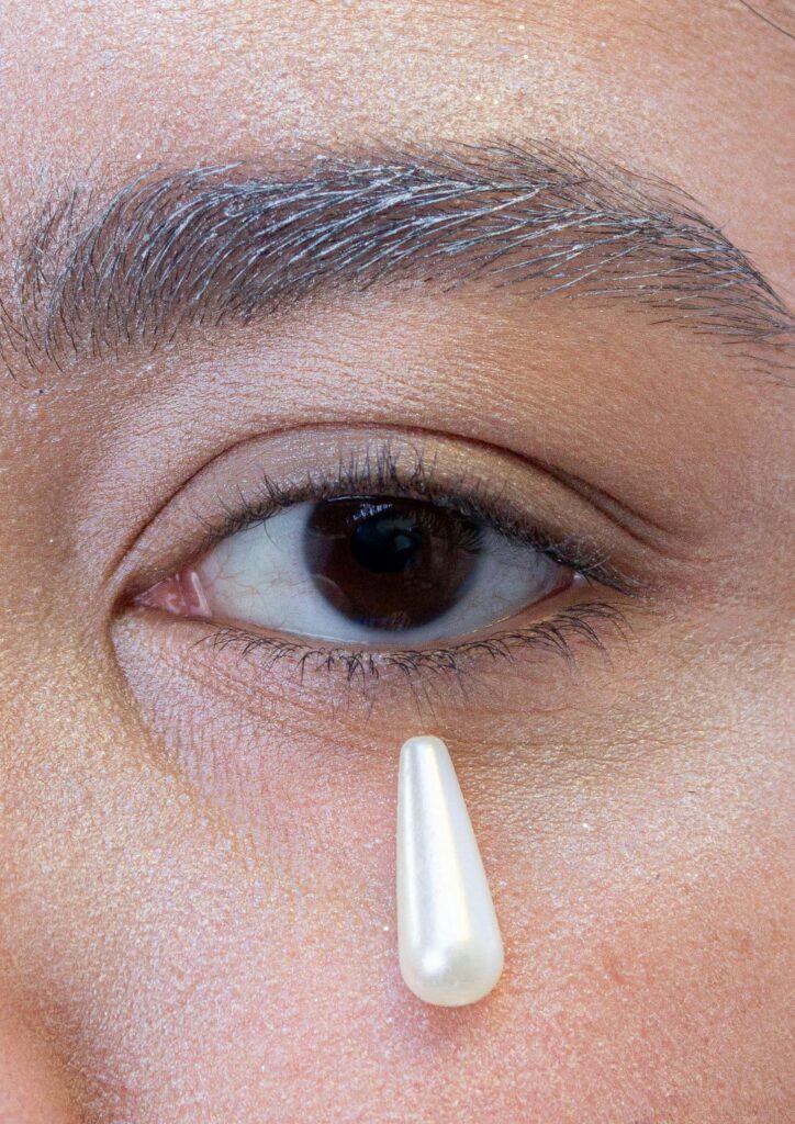 Artistic close-up of an eye with a teardrop-shaped pearl, symbolizing emotion.